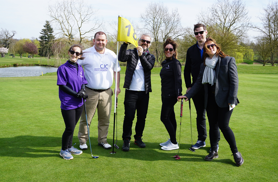 People standing on gold green at hole 18