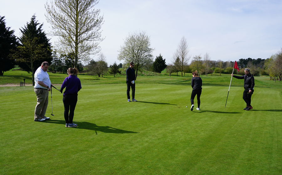 group of people standing on putting green