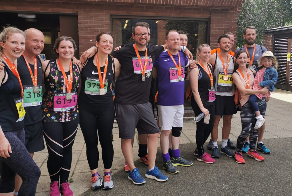 indigo Swan team members in running gear wearing medals