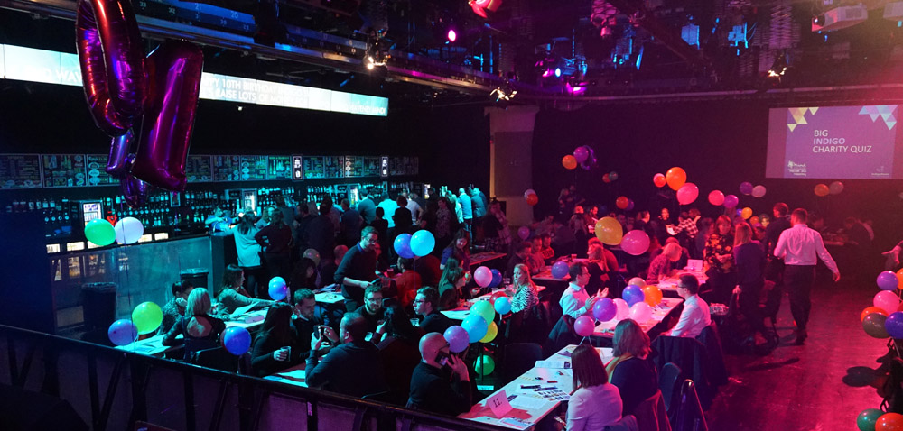 Room full of people sitting at tables taking part in a quiz